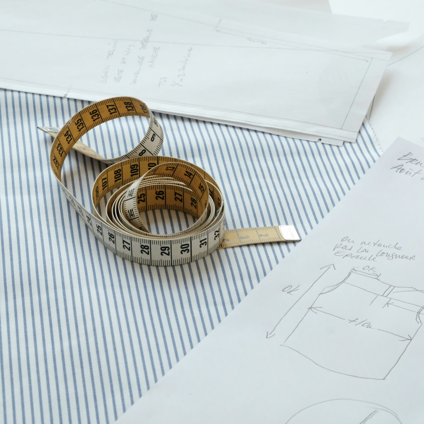 Scrivania da sarto con stoffa, metro e schizzi di design francesi.