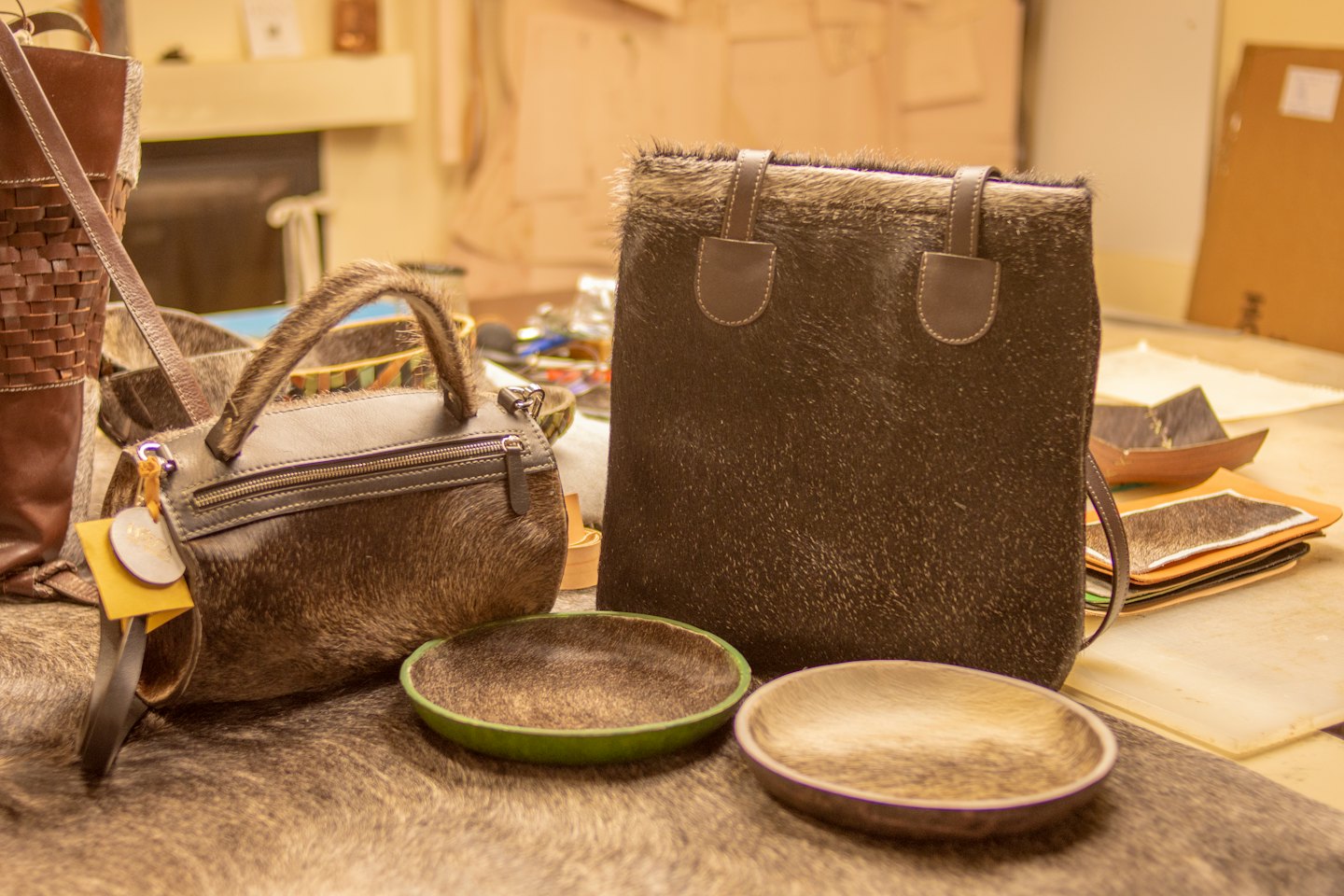 Borsa in pelle, shopper e piatti su una superficie di pelliccia.